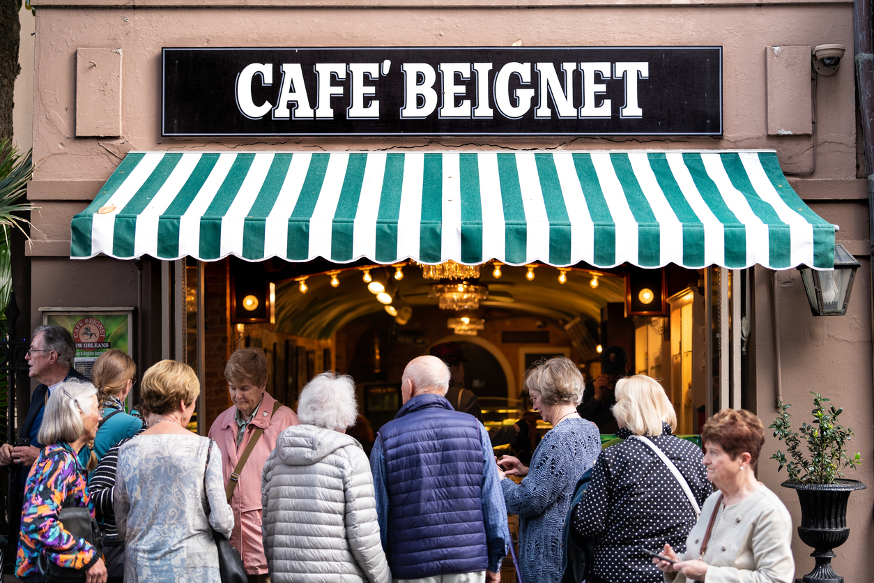 People in line queue during day for famous restaurant cafe beignet powdered sugar donuts People in line queue during day for famous restaurant cafe beignet powdered sugar donuts.