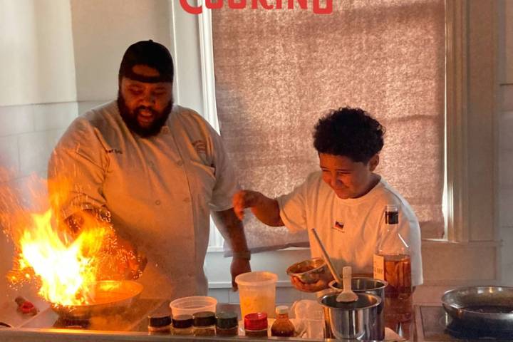 Chef and child cooking with flames at New Orleans School of Cooking.