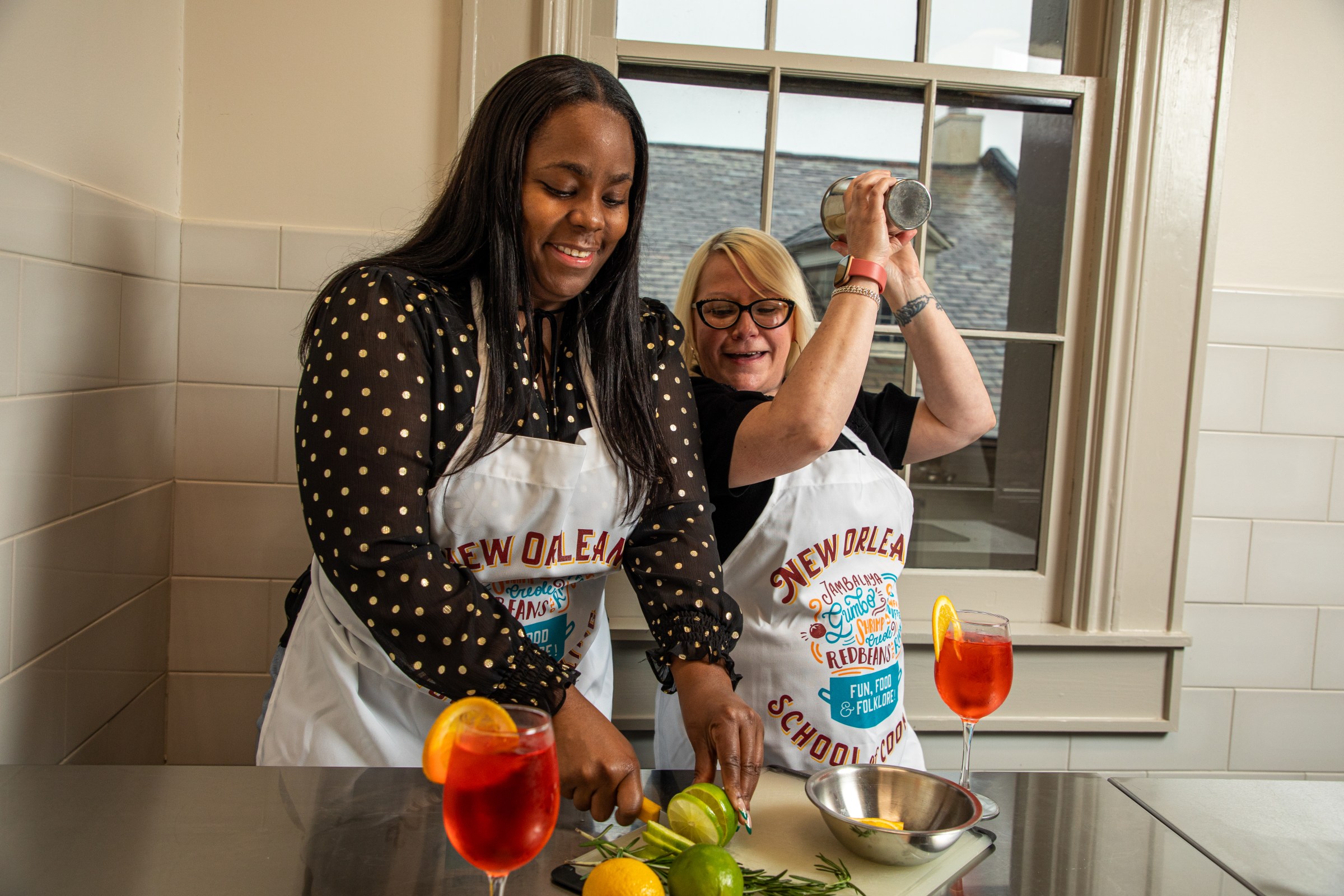 Two women preparing and shaking cocktails together during a NOSOC mixology class.