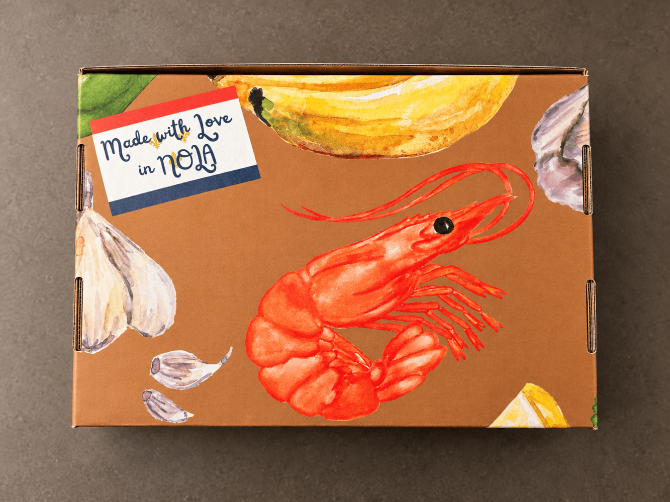 Box with shrimp, garlic, banana artwork, reads 'Made with love in NOLA'.